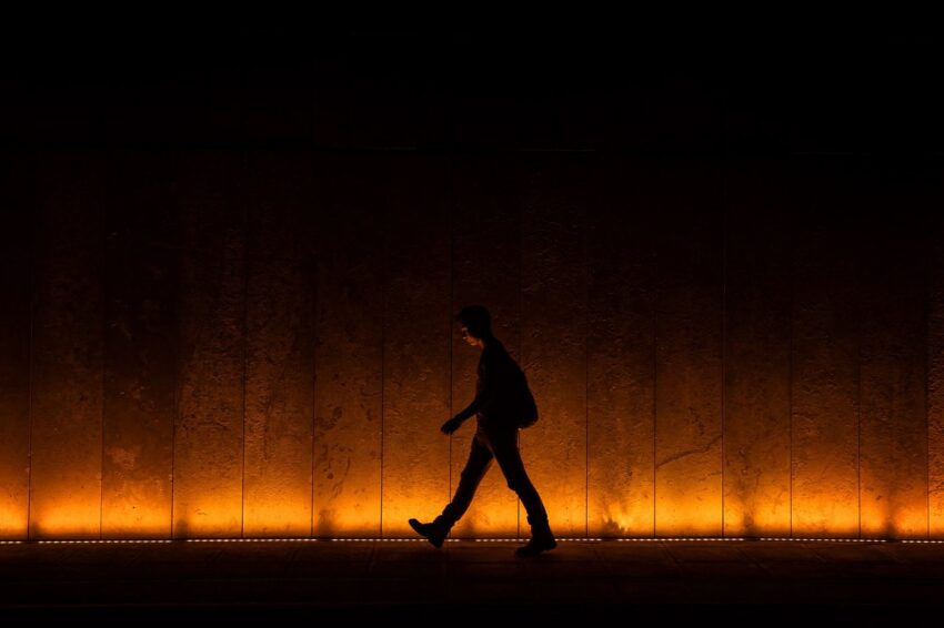Man walking on lighted sidewalk at night
